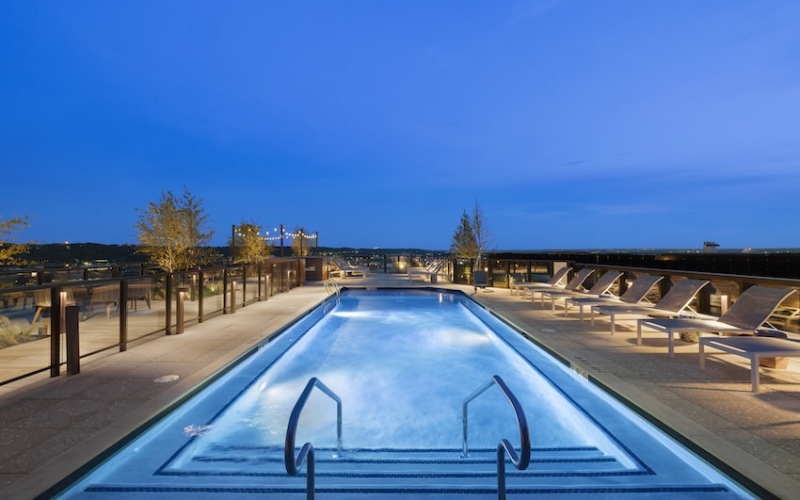 rooftop pool with  wood deck with trees and blue evening sky